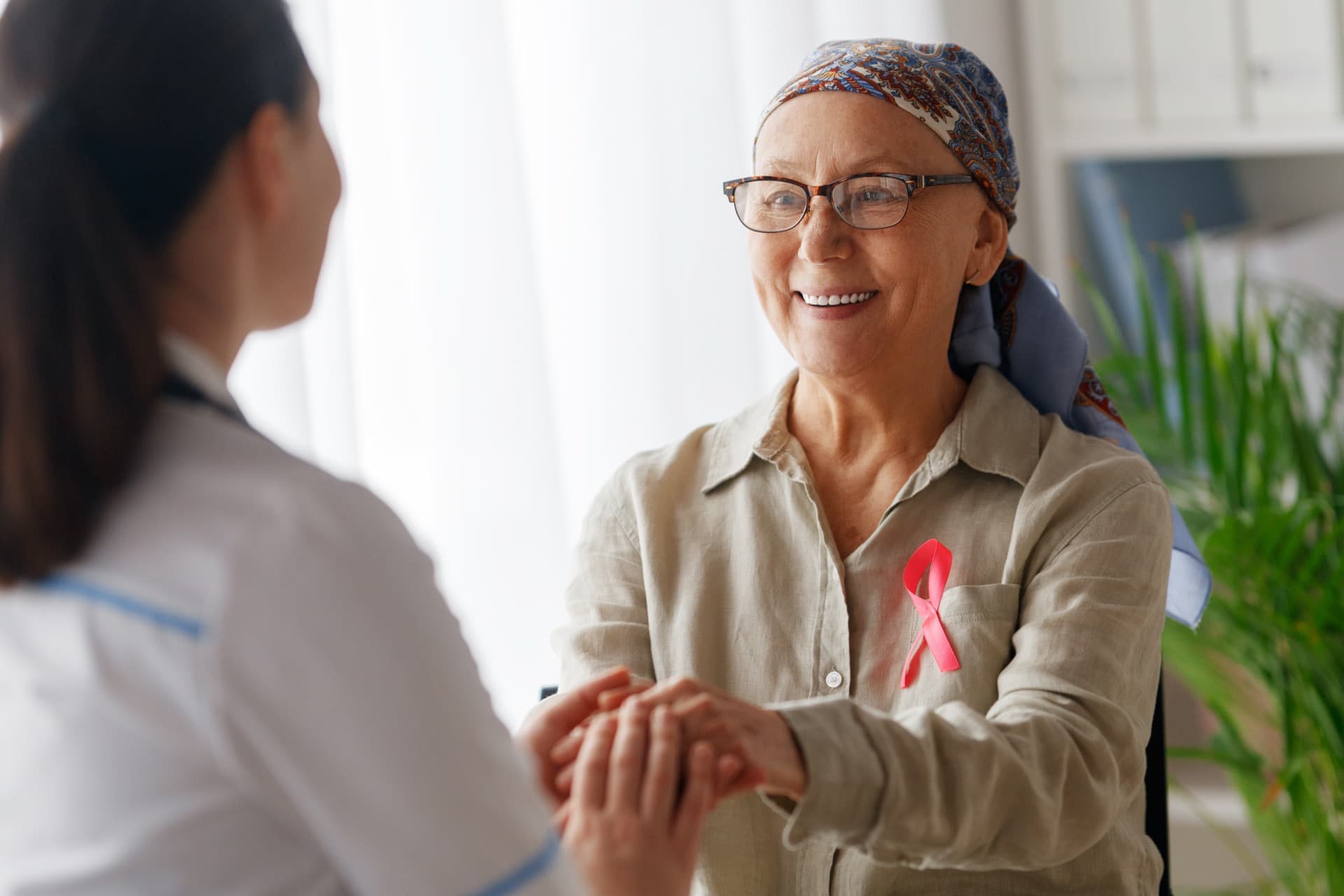 Une patiente atteinte de cancer souriante tenant la main d'une soignante